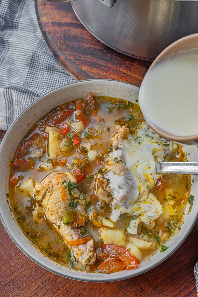 pouring cream into chicken soup for creamy chicken and vegetable soup